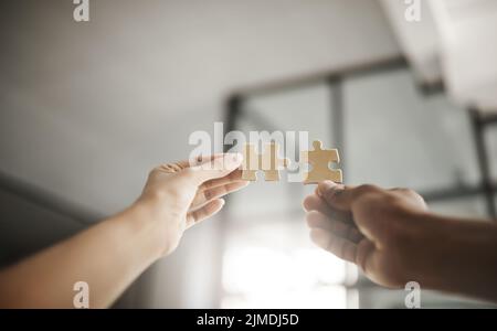 Closeup hands of partners in unity, planning and working on strategy puzzle piece game. People collaborating on innovative jigsaw parts to fit Stock Photo