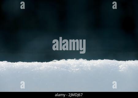 Selective focus on the surface of fresh snow on a dark background. Stock Photo