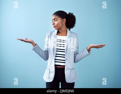 Professional black corporate business woman making a hand gesture for decision, choice and balance while standing against a blue studio background Stock Photo