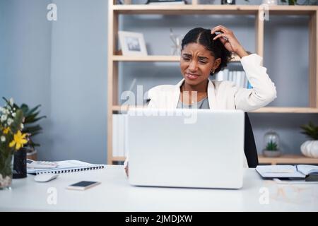 Confused, stressed and angry business woman reading email and scratching her head thinking in her office. A young African American corporate female Stock Photo