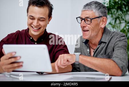 This app has been quite handy for us. two businessmen working together on a digital tablet in an office. Stock Photo