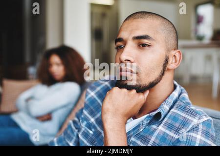 Unhappy couple after argument with a frustrated, upset and sad husband looking away from his wife at home. Depressed and distant boyfriend sitting on Stock Photo