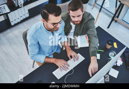 Working together with cohesion. two young designers working together on a computer in an office. Stock Photo