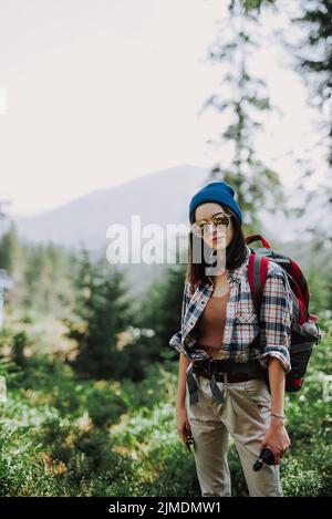 Portrait of attractive girl in a hat with a vape and phone. Hipster girl on the top of the mountain smoking. Women hiker with a Stock Photo