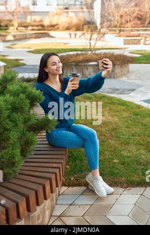 Charming lady posing for selfie on a bench in beautiful square Stock Photo