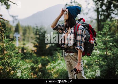 Girl traveler in a hat stands on the top of the mountain. Hipster girl on the top of the mountain smoking the vape.  Stylish hik Stock Photo