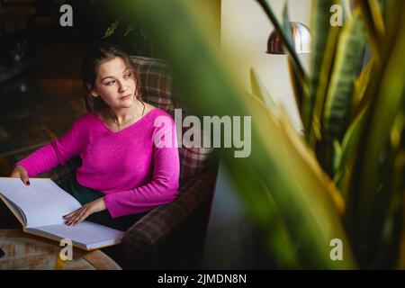 Smiling young woman looking out the window in cafeteria Stock Photo