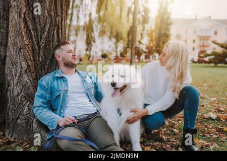 Smiling couple spending time outdoors with their puppy pet Stock Photo