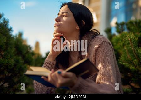 Serious woman thinking about something while reading outdoors Stock Photo