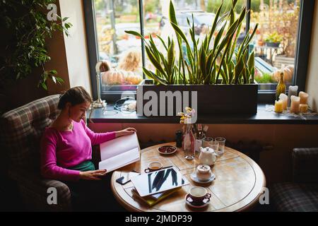 Pretty young woman studying in cozy cafe Stock Photo