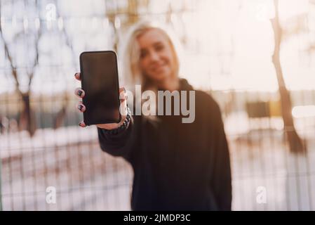 Happy young woman is showing mobile phone Stock Photo