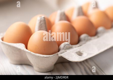 Chicken eggs in cardboard box on wooden table. Egg Yolk Cooking Stock Photo