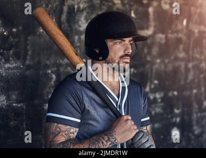 In a league of his own. a young man holding his bat at a baseball game. Stock Photo