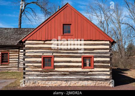 Red peaked roof and log construction of a colonial house Stock Photo