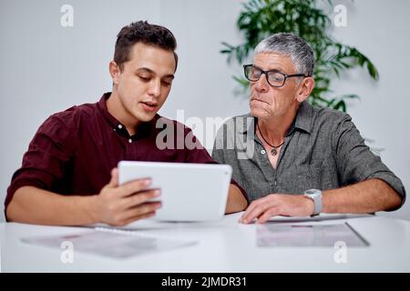 Digitally devising something new. two businessmen working together on a digital tablet in an office. Stock Photo