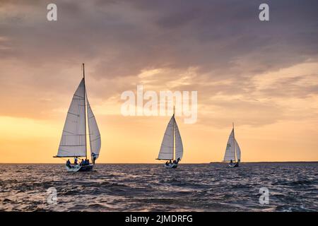 Russia, St.Petersburg, 05 September 2020: Some sailboats in a list goes by sea, the sky of pink color, the storm sky, regatta Stock Photo