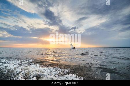 Russia, St.Petersburg, 05 September 2020: The lonely sailboat in a list goes by sea, the sky of pink color, the storm sky Stock Photo