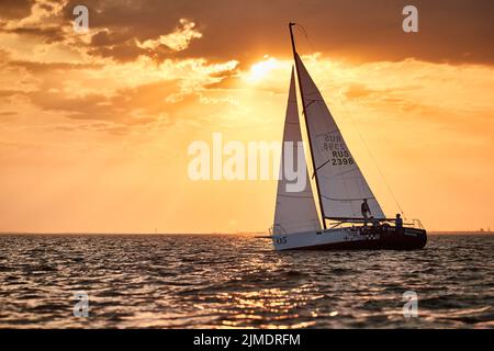 Russia, St.Petersburg, 05 September 2020: The lonely sailboat in a list goes by sea, the sky of pink color, the storm sky Stock Photo