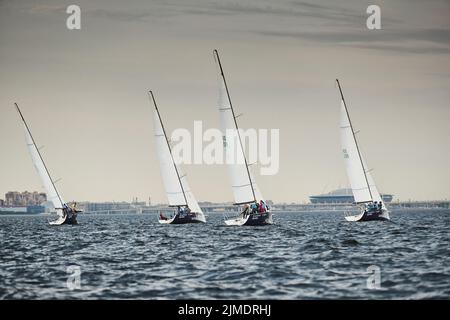 Russia, St.Petersburg, 05 September 2020: Some sailboats in a list goes by sea, the storm sky, regatta, Gazprom arena stadium on Stock Photo