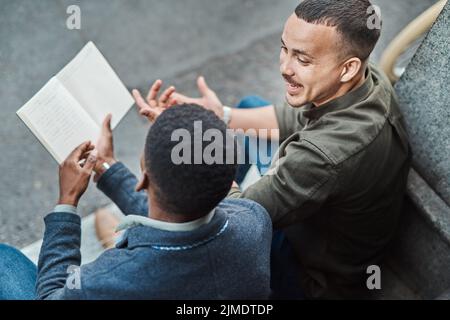 Set goals then get going. two young businessmen having an informal meeting against an urban background. Stock Photo