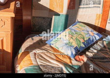 morning light and colorful pillow on unmade bed, indoor close up Stock Photo