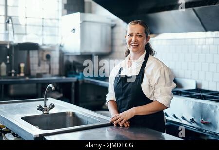 Watch me make culinary magic. Portrait of a confident mature woman standing in the kitchen of her cafe. Stock Photo