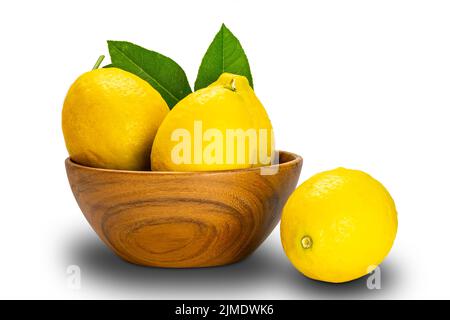 Ripe lemons with leaves in a wooden bowl on white background. Stock Photo