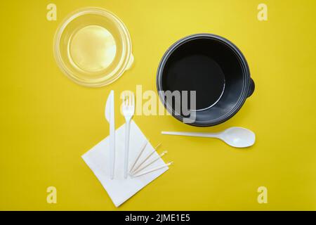 Disposable plastic tableware on yellow background Stock Photo