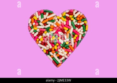 Heart shaped colorful rainbow sprinkles isolated on pink background. Stock Photo