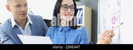 In the office, a couple look at a whiteboard with a diagram Stock Photo