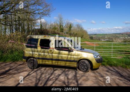 EXETER, DEVON, UK -  MARCH 31, 2022 a Peugeot Partner vehicle abandoned on a quiet country lane and burnt out with smashed windscreen Stock Photo