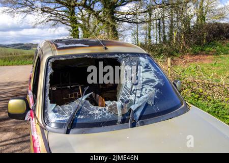 EXETER, DEVON, UK -  MARCH 31, 2022 a Peugeot Partner vehicle abandoned on a quiet country lane and burnt out with smashed windscreen Stock Photo