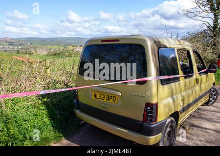 EXETER, DEVON, UK -  MARCH 31, 2022 a Peugeot Partner vehicle abandoned on a quiet country lane and burnt out with smashed windscreen Stock Photo