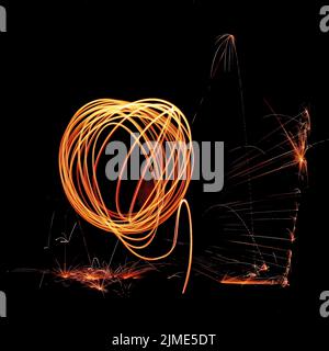 Steel wool spinning in a tunnel, throwing off yellow and orange sparks making a spinning pattern Stock Photo