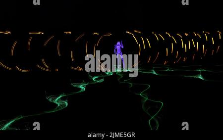 light painting at night with a slow shutter speed on the camera making vibrant patterns in the night. Stock Photo