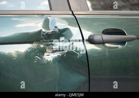 A dent on the car door. Damaged transport. A wrecked car. Stock Photo