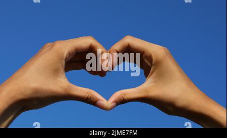 Joined Hands Forming A Heart On The Sky In The Background Stock Photo 