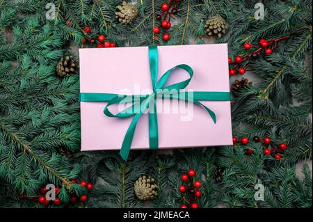 Christmas gift. Gift box and Christmas decorations. Christmas composition. Frame made of christmas gifts, dark pine branches on green background. Flat Stock Photo