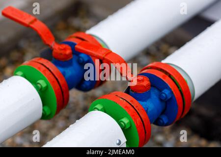 New shut-off valves pipeline close-up. These are white pipes and a red valve. Stock Photo