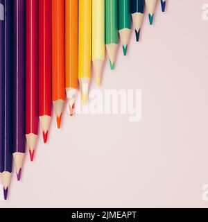 Colored pointed pencils lie on a pink background with space for copying. School supplies or school preparation. Stock Photo