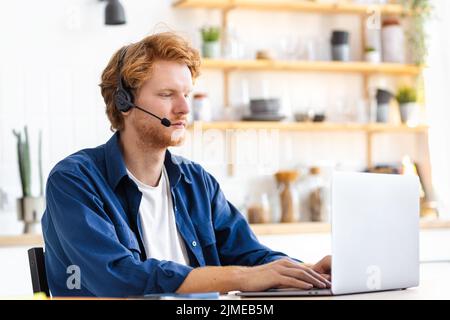 concentrated man student in headset using laptop sitting in home distance learning online education Stock Photo