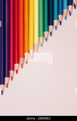 Colored pointed pencils lie on a pink background with space for copying. School supplies or school preparation. Stock Photo