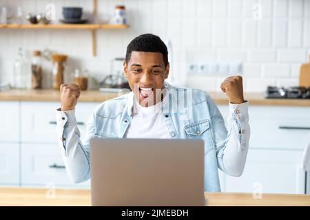 Excited African American man freelancer or student reading good news in email Stock Photo
