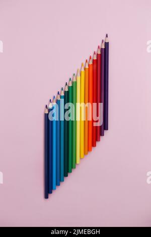 Colored pointed pencils lie on a pink background with space for copying. School supplies or school preparation. Stock Photo