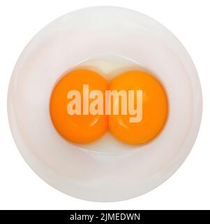 Two raw chicken eggs cracked into a bowl. Yolk and white without eggshells. Common food and versatile ingredient in cooking. Isolated macro food photo Stock Photo