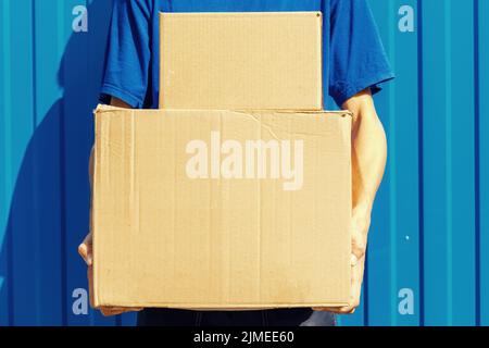 The courier holds cardboard boxes in his hands. Close-up with space to copy. Stock Photo