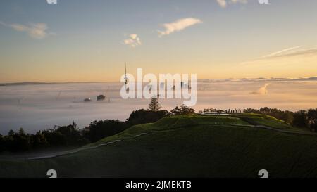 Sky Tower and Auckland city in the fog at sunrise, from Mount Eden summit. Stock Photo