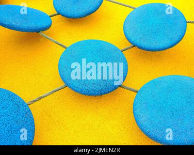 Blue circles connected by a rope on a bright yellow background. Stock Photo