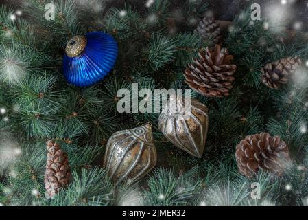 Various Christmas decorations and pine cones on green fir branches background. Stock Photo