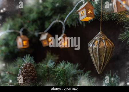 Christmas tree garland in the form of small Scandinavian houses cozy on a fir tree branch. Stock Photo